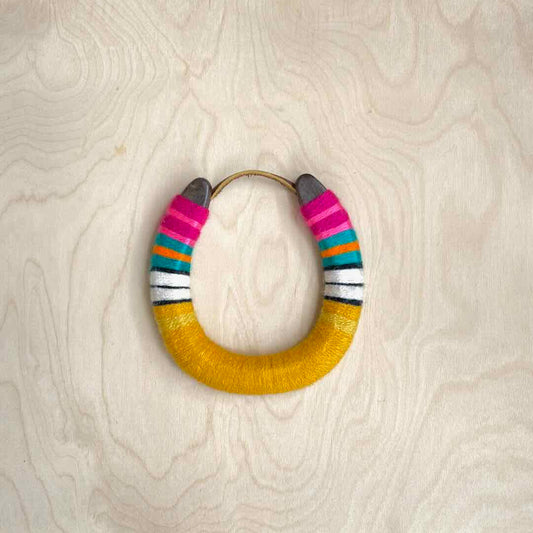 Colorful yarn wrapped horseshoe with pink top and golden yellow bottom.