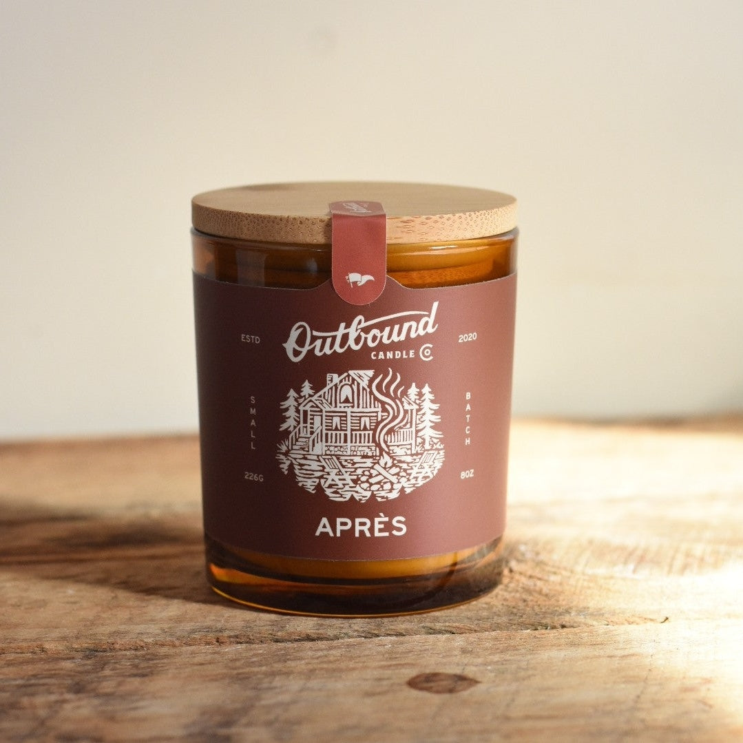Apres Candle with a wooden lid and 'Outbound Candle Co' label on a wooden surface
