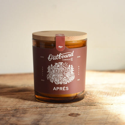 Apres Candle with a wooden lid and 'Outbound Candle Co' label on a wooden surface
