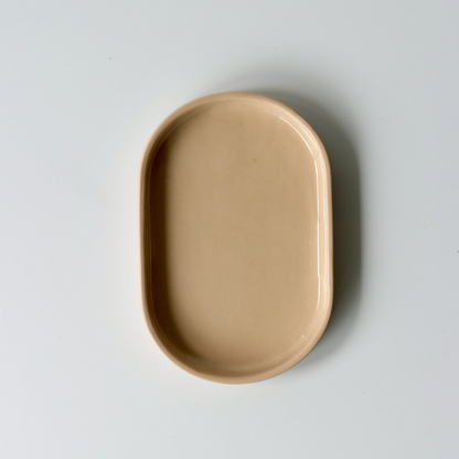 Peach oval shaped ceramic dish on a light gray background