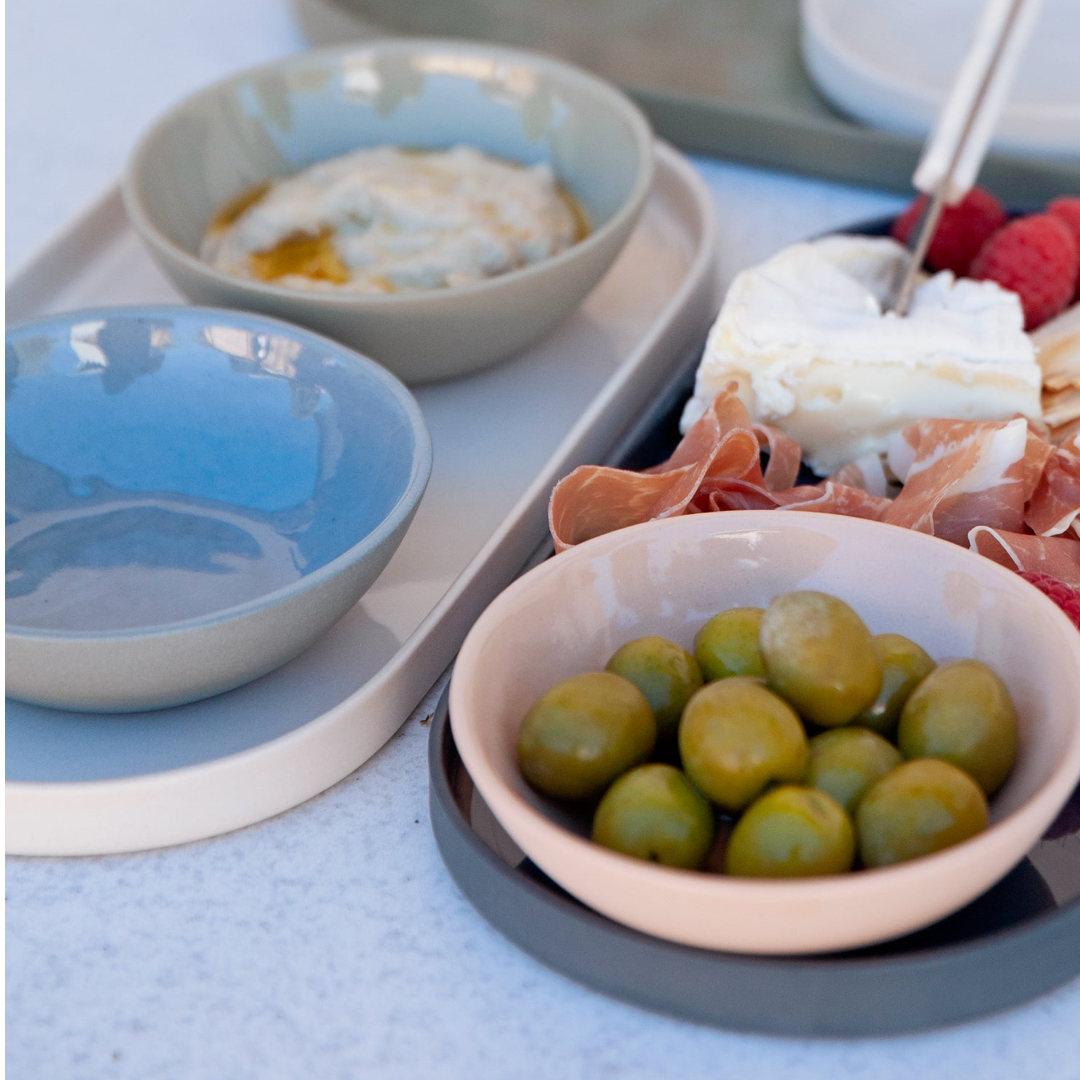 Assorted food items including olives, cheese, and fruit on a tray with bowls.