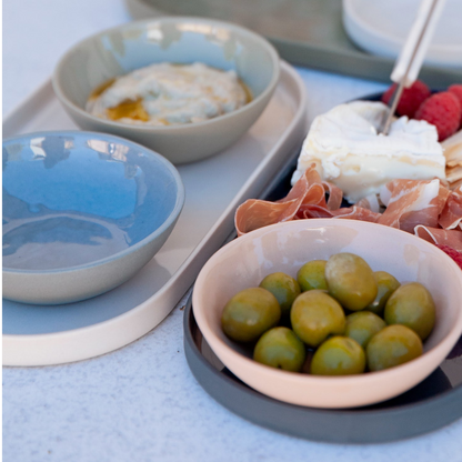 Assorted food items including olives, cheese, and fruit on a tray with bowls.