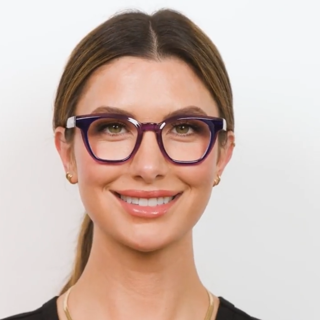 Woman wearing purple glasses against a plain background