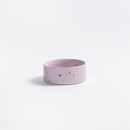 Pink ceramic bowl with multicolored speckles on a light gray background