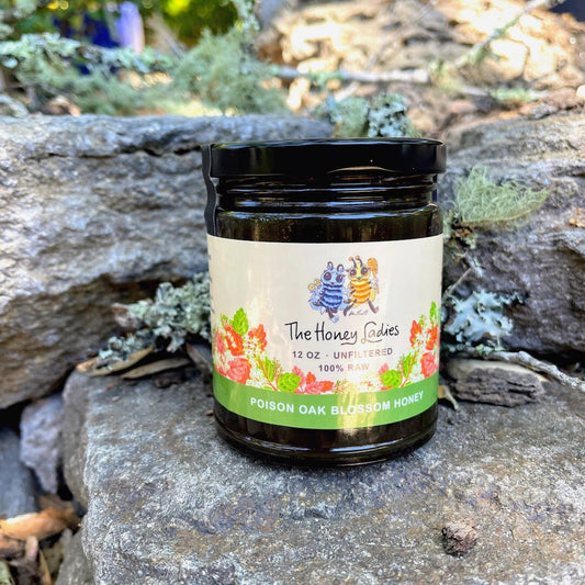 Jar of 'The Honey Ladies' poison oak blossom honey on a stone surface with natural background