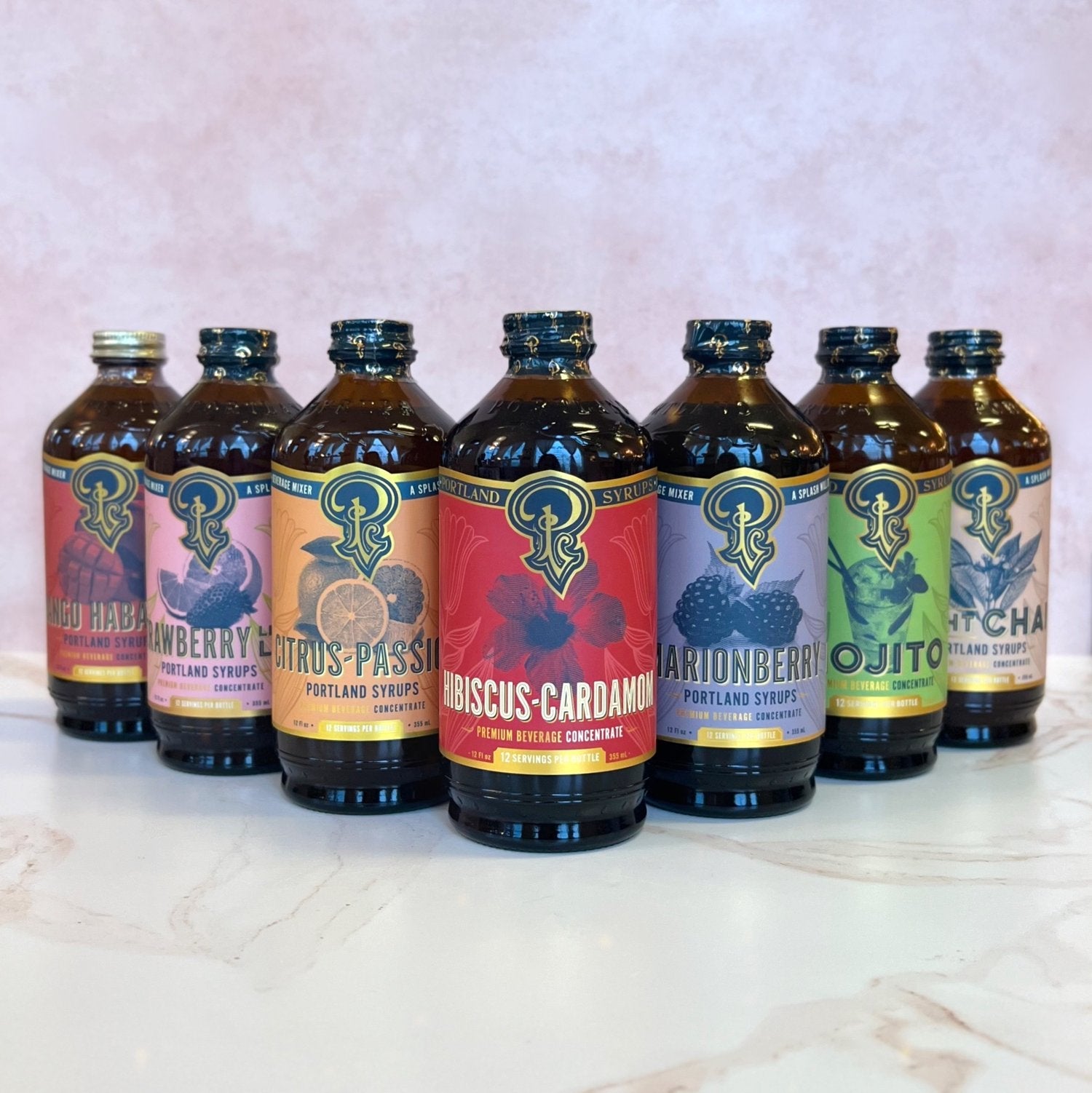 Row of Portland Syrup bottles with colorful labels on a marble surface.
