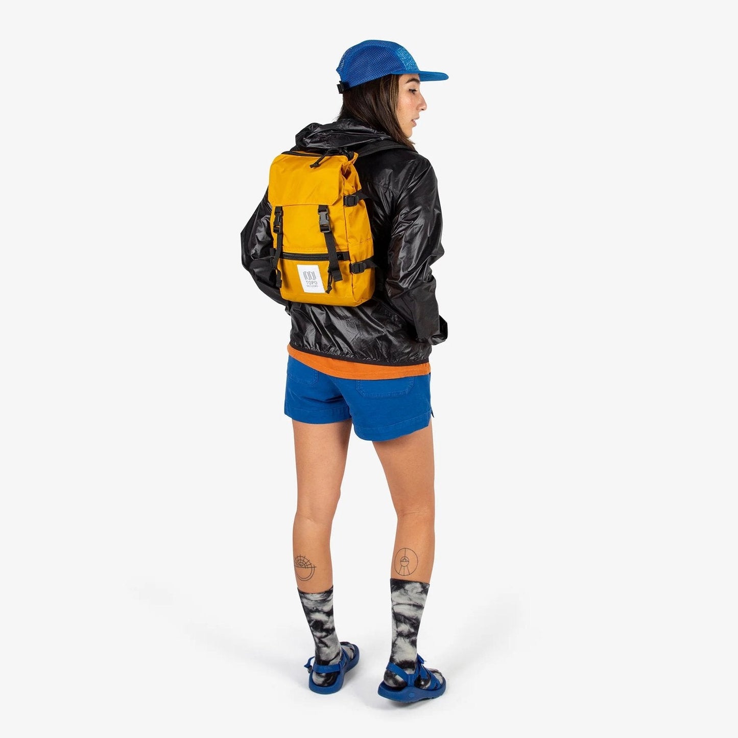 Person wearing a yellow backpack and blue cap on a white background