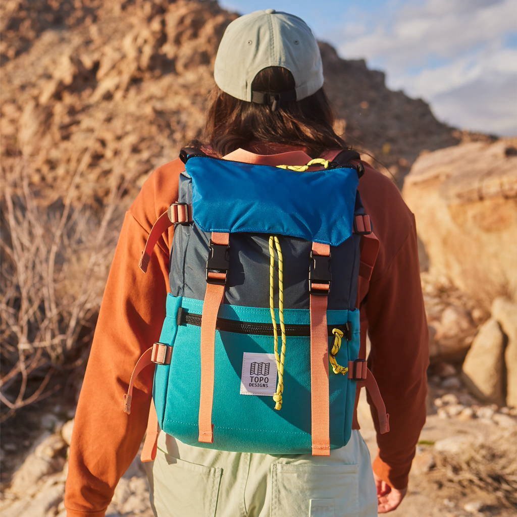 Person wearing a colorful backpack with a mountainous landscape in the background