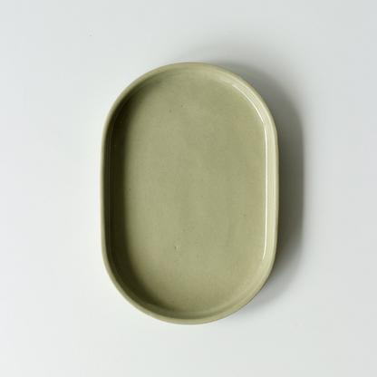 Sage green oval shaped ceramic dish on a white background