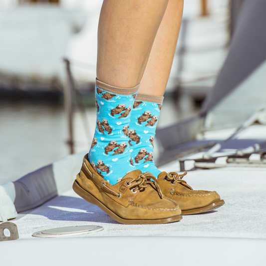 Person wearing blue socks with an otter pattern and brown shoes on a boat.