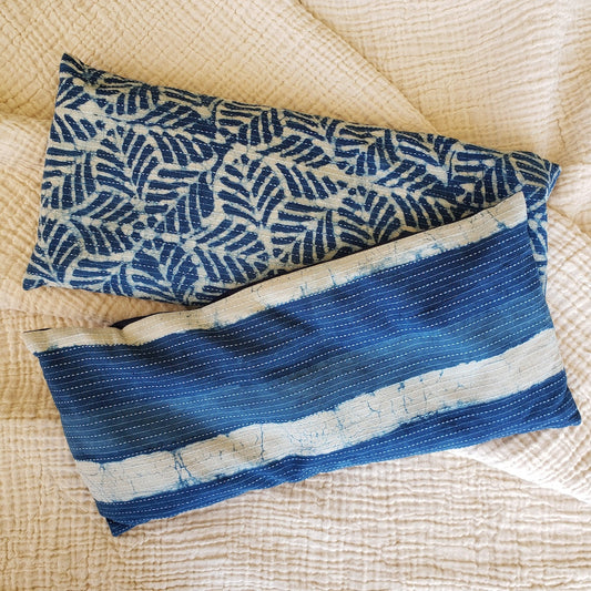 Two blue patterned pillows on a textured beige surface