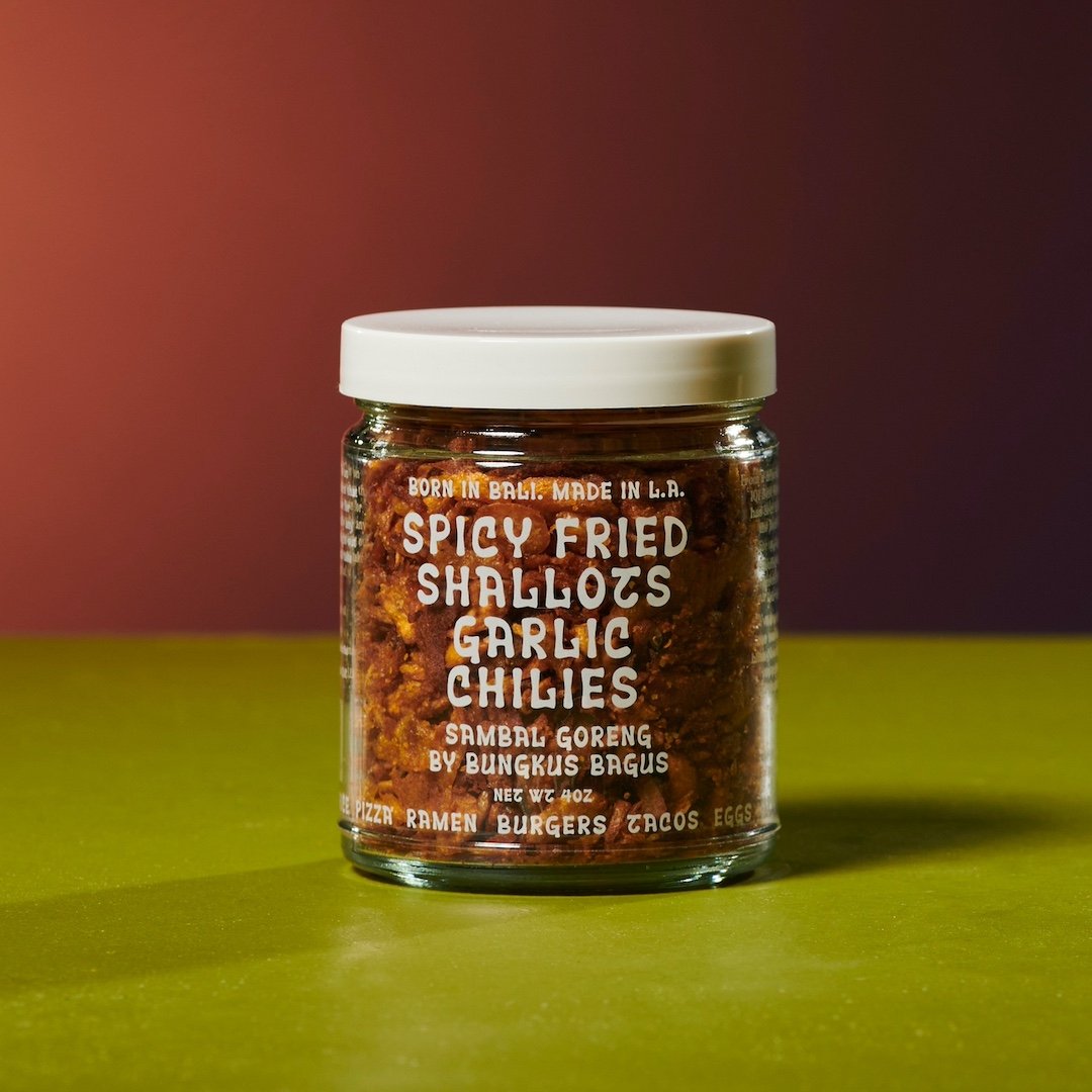 Jar of spicy fried shallots garlic chilies on a green surface with a red background