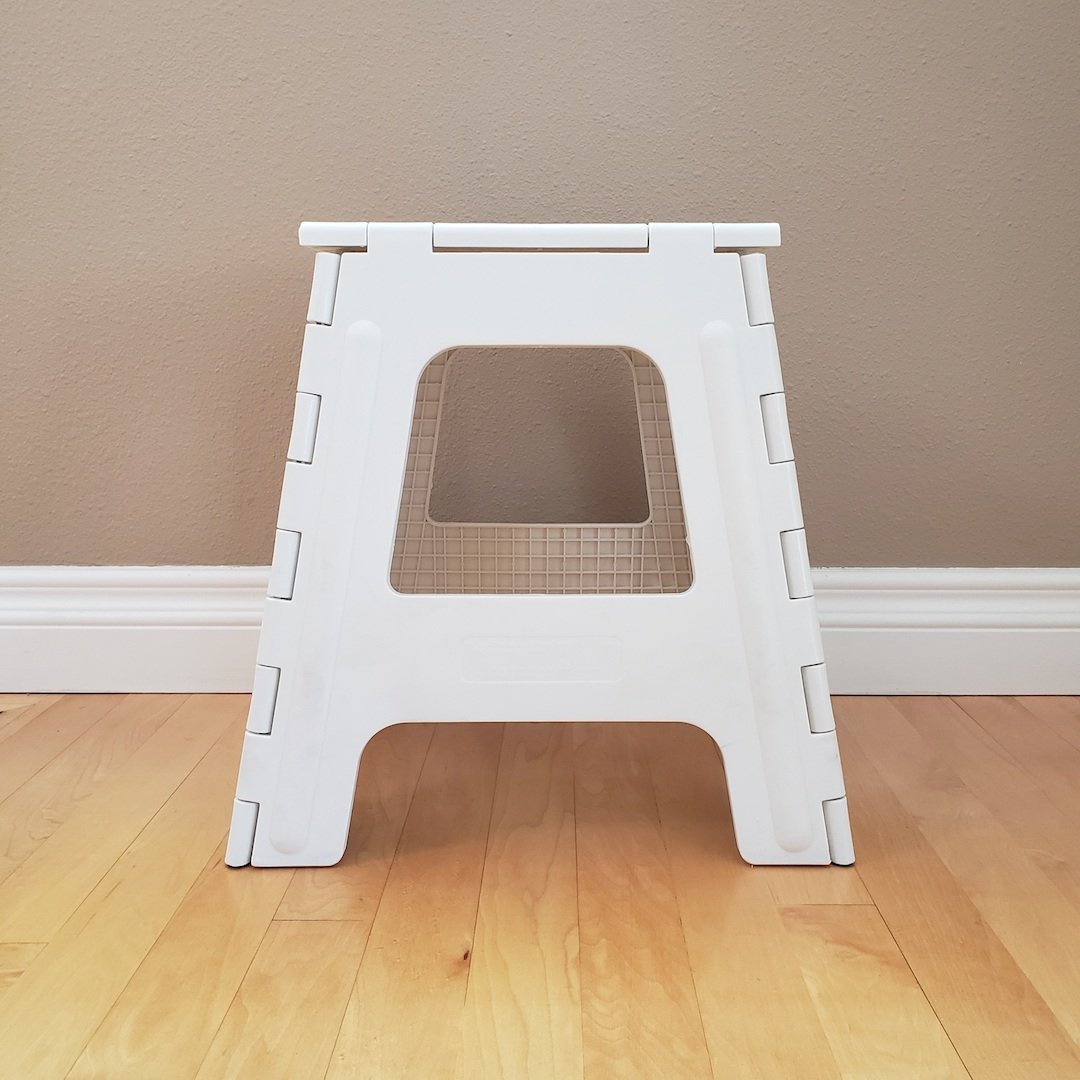 White step stool on a wooden floor.