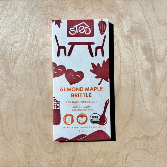 Almond Maple Brittle chocolate bar in packaging on a wooden surface