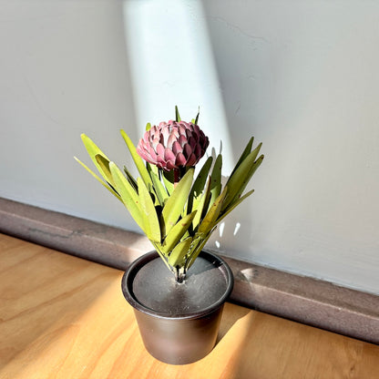 Aluminum dahlia in a pot on a wooden table.