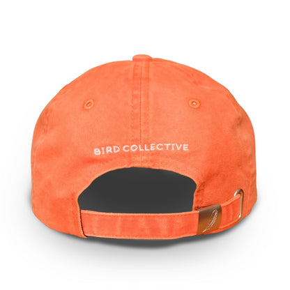 The back of an orange cotton baseball cap with 'BIRD COLLECTIVE' embroidered in white and an adjustable strap 