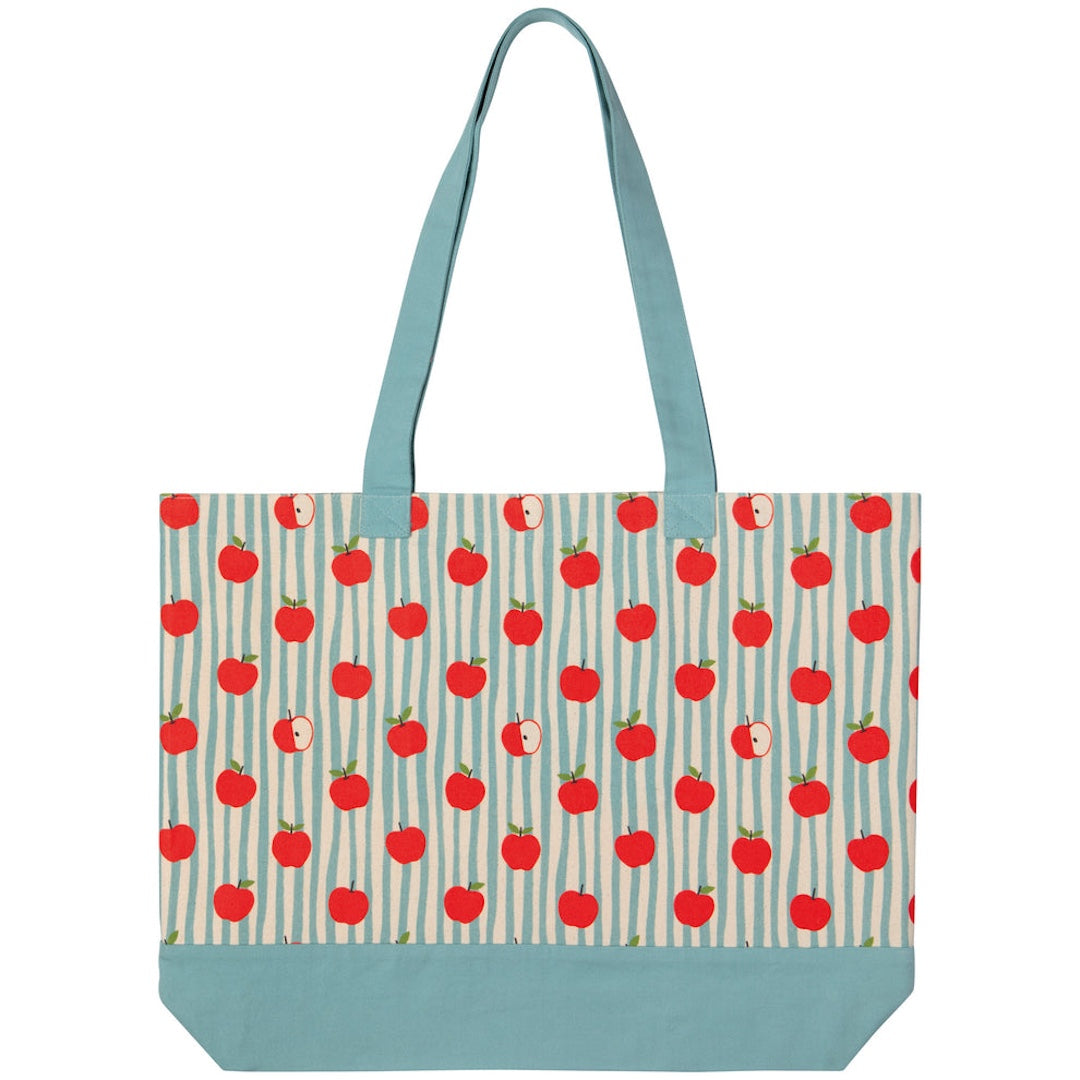 A canvas tote bag with a repeating pattern of red apples on a light blue and white striped background, featuring solid light blue handles and a solid light blue bottom base.