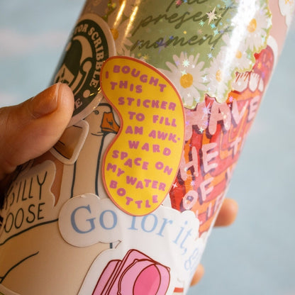 Collection of colorful stickers on a water bottle held by a hand with a light blue background