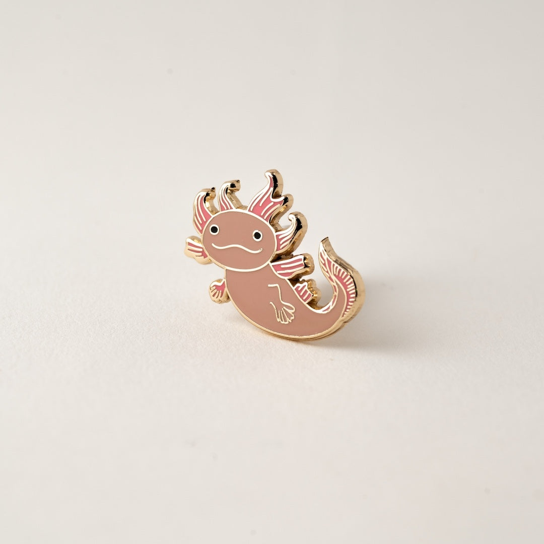 Axolotl-shaped pin on a light beige background