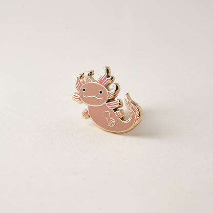 Axolotl-shaped pin on a light beige background
