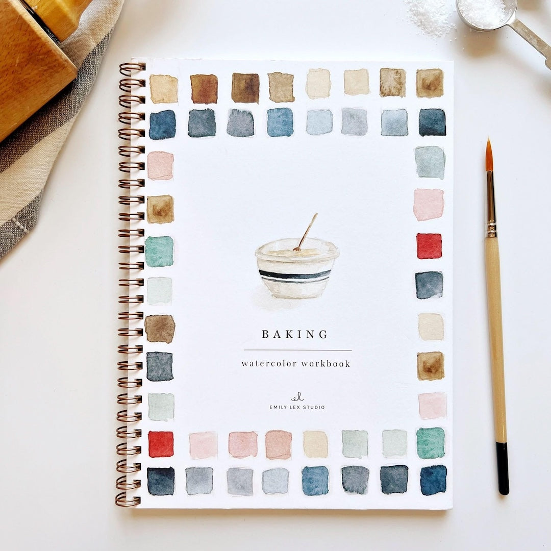 Spiral-bound notebook with watercolor design and 'Baking watercolor workbook' text on a white surface.