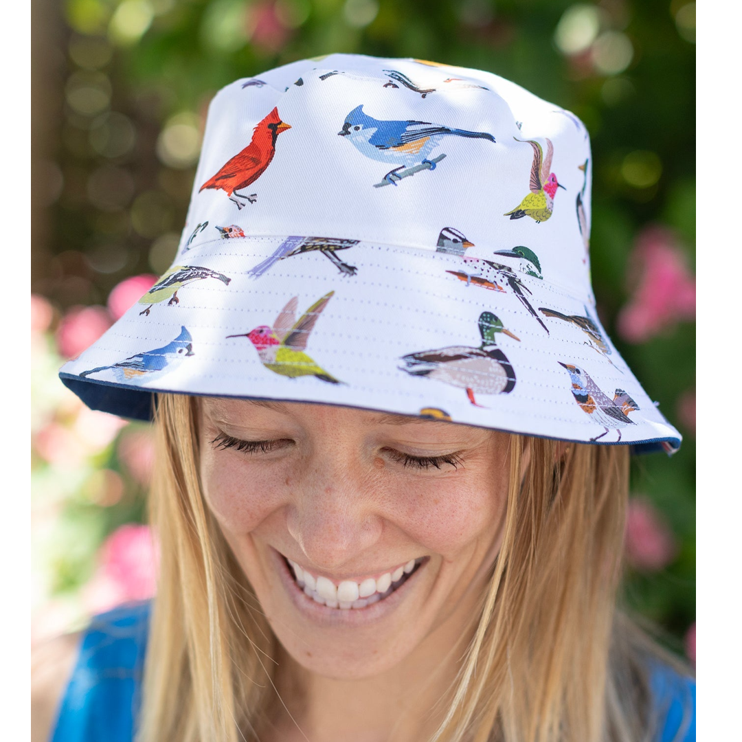 Person wearing a bucket hat with bird pattern against a blurred natural background