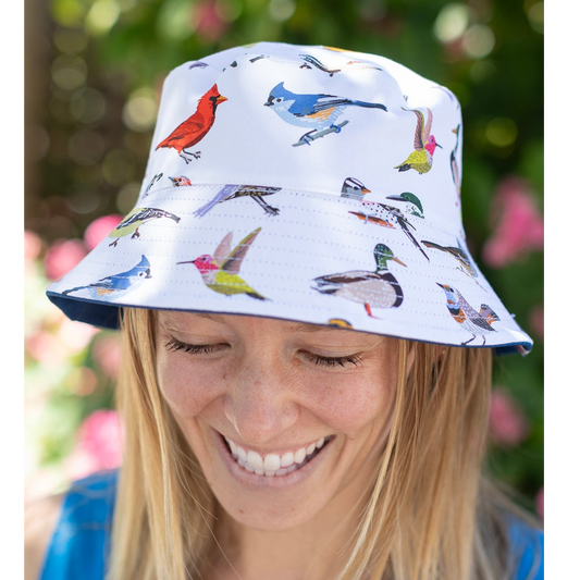 Person wearing a bucket hat with bird pattern against a blurred natural background