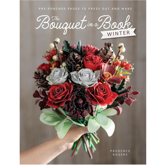Book cover for 'The Bouquet in a Book: Winter' by Prudence Rogers, featuring a hand holding a colorful paper flower bouquet with red roses, white and gray roses, pinecones, and green leaves against a soft gray background.
