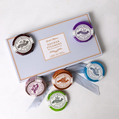 Set of shower steamers with a branded box on a white background