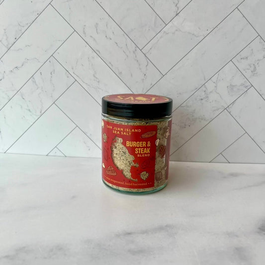 Jar of 'Burger & Steak Blend' seasoning on a marble surface with a white tiled wall background