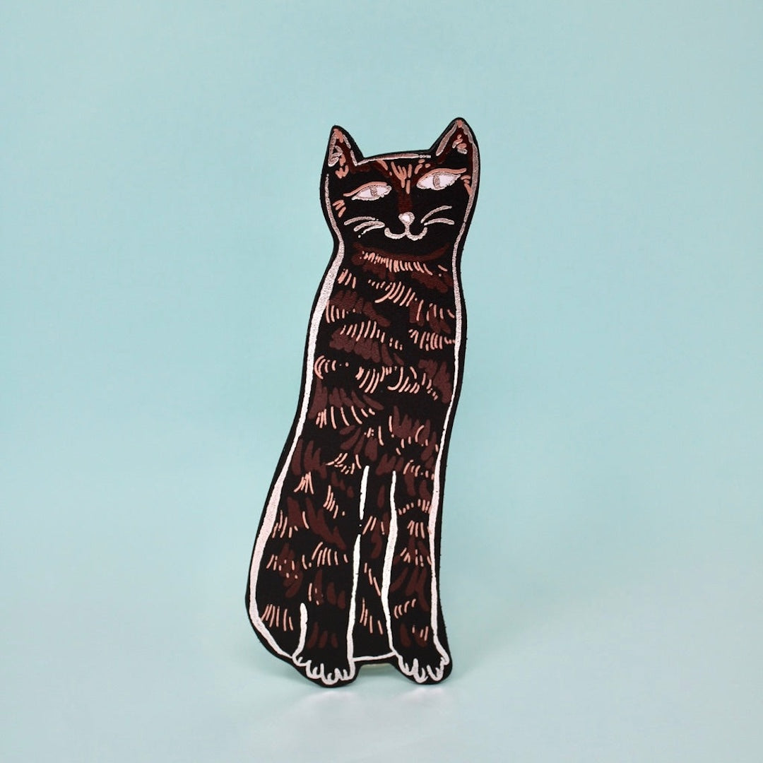 black cat shaped leather bookmark on a light blue background