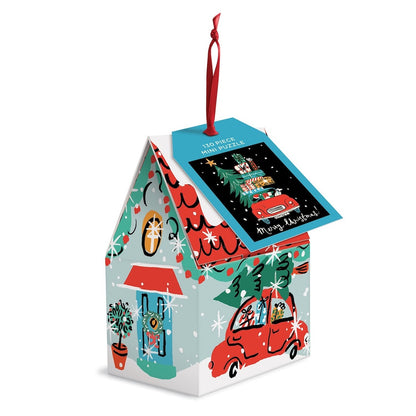 A Christmas-themed mini puzzle box shaped like a house, featuring festive illustrations of a red car, Christmas tree, potted plant, and a red hanging ribbon. A blue card on top reads '130 PIECE MINI PUZZLE' and 'Merry Christmas'.