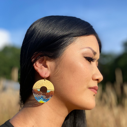Woman wearing colorful earrings with a blurred natural background