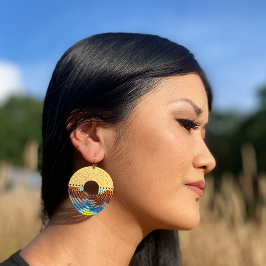 Woman wearing colorful earrings with a blurred natural background