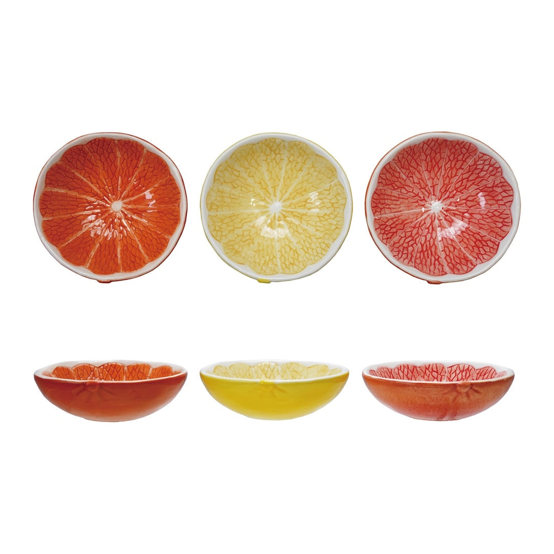 Set of three ceramic bowls shaped like sliced a grapefruit, lemon, and an orange on a white background