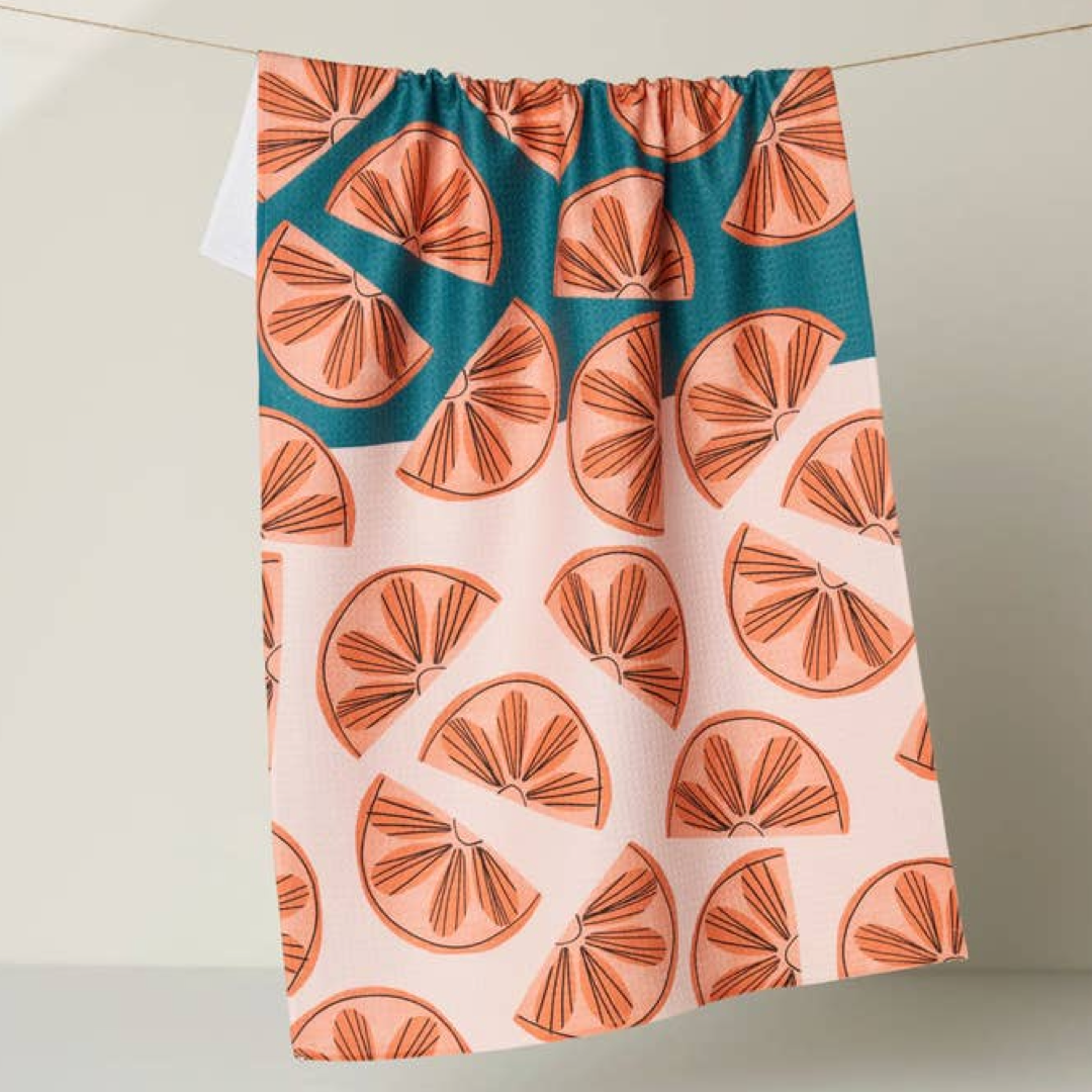 Dishtowel with orange slice pattern on a teal and pink background