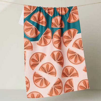 Dishtowel with orange slice pattern on a teal and pink background