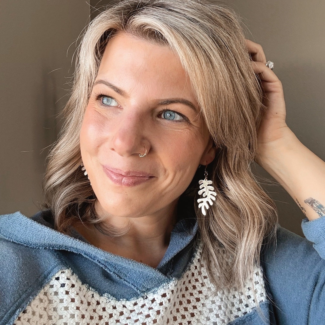 Woman with blonde hair wearing a blue sweater posing against a neutral background.