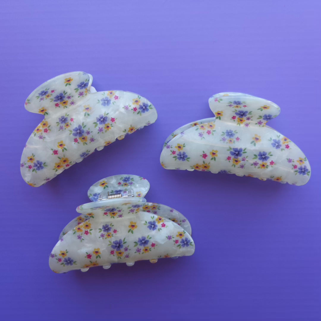 Set of three floral-patterned hair clips on a purple background