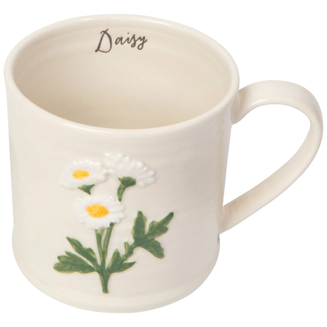 white mug with some daisies on the front. Inside the mug the word "daisy" is written in cursive