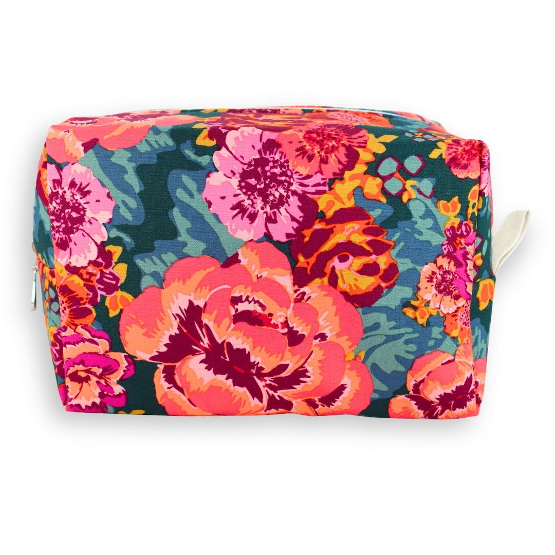 A rectangular zippered pouch with a vibrant floral print featuring large pink, orange, and red flowers on a dark teal background, with a small white loop handle on the right side.
