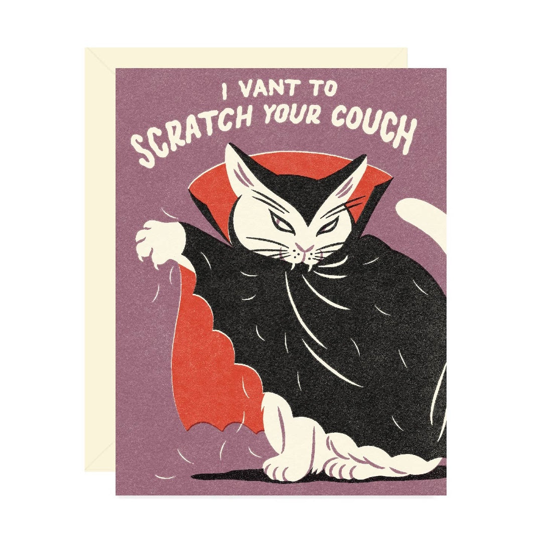 A humorous greeting card featuring a cartoon illustration of a cat dressed as a vampire, with the text 'I WANT TO SCRATCH YOUR COUCH' on a mauve background. A cream-colored envelope is visible behind the card.