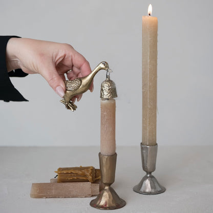 Decorative candle holders with a hand holding a gold duck shaped candle snuffer
