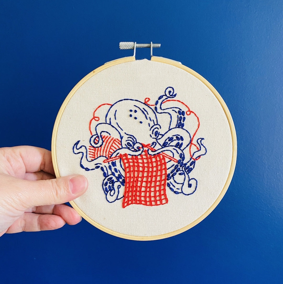 Embroidery hoop with an octopus knitting design on a blue background