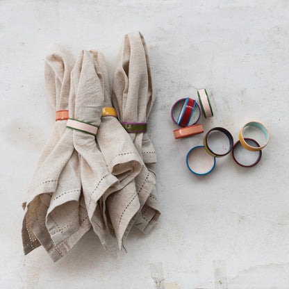 Beige napkin with colorful napkin rings on a light gray surface