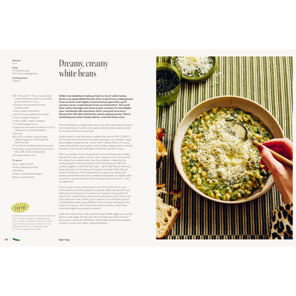 An open cookbook spread showing a recipe page titled 'Dreamy, creamy white beans' on the left and a food photograph of a bowl of white beans topped with cheese on the right.