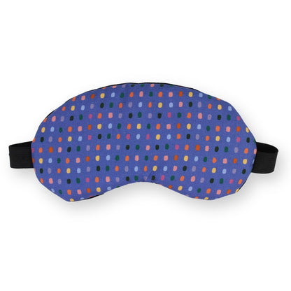 A sleep mask with a purple base and a colorful pattern of small, colored dots, featuring black adjustable straps on a plain white background.