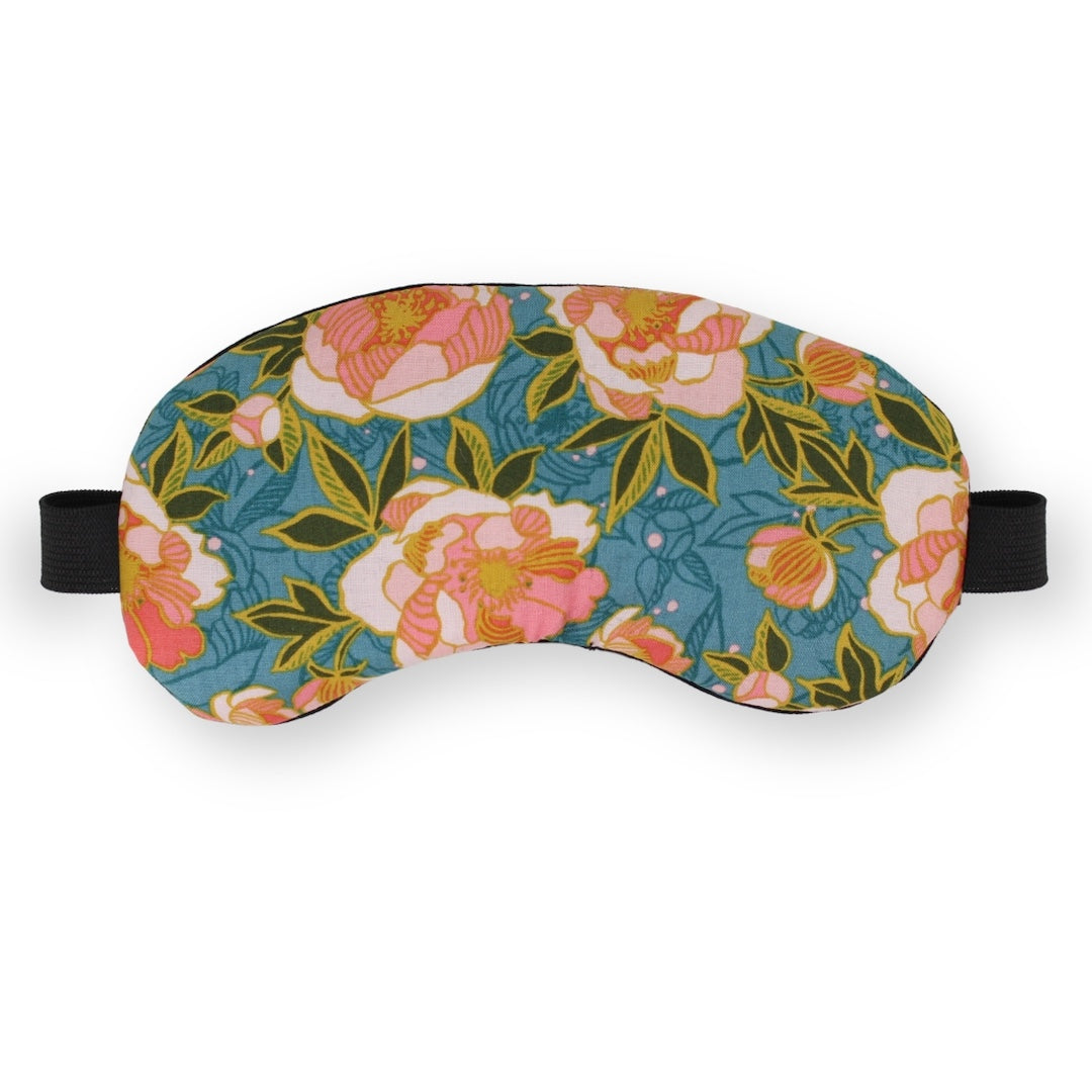 A sleep mask with a vibrant floral pattern featuring pink and white peonies, green leaves, and a teal blue background, complete with black adjustable straps on a clean white background.