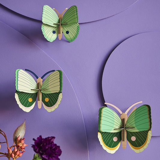 Three green butterfly wall hangings on a purple background