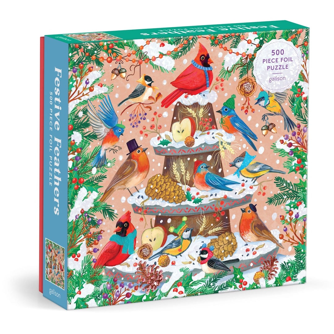 A 500-piece foil puzzle box by The Puzzle Company titled 'Festive Feathers' featuring a colorful winter illustration of birds, cardinals, squirrels, pinecones, and berries on a snowy tree against a beige background.